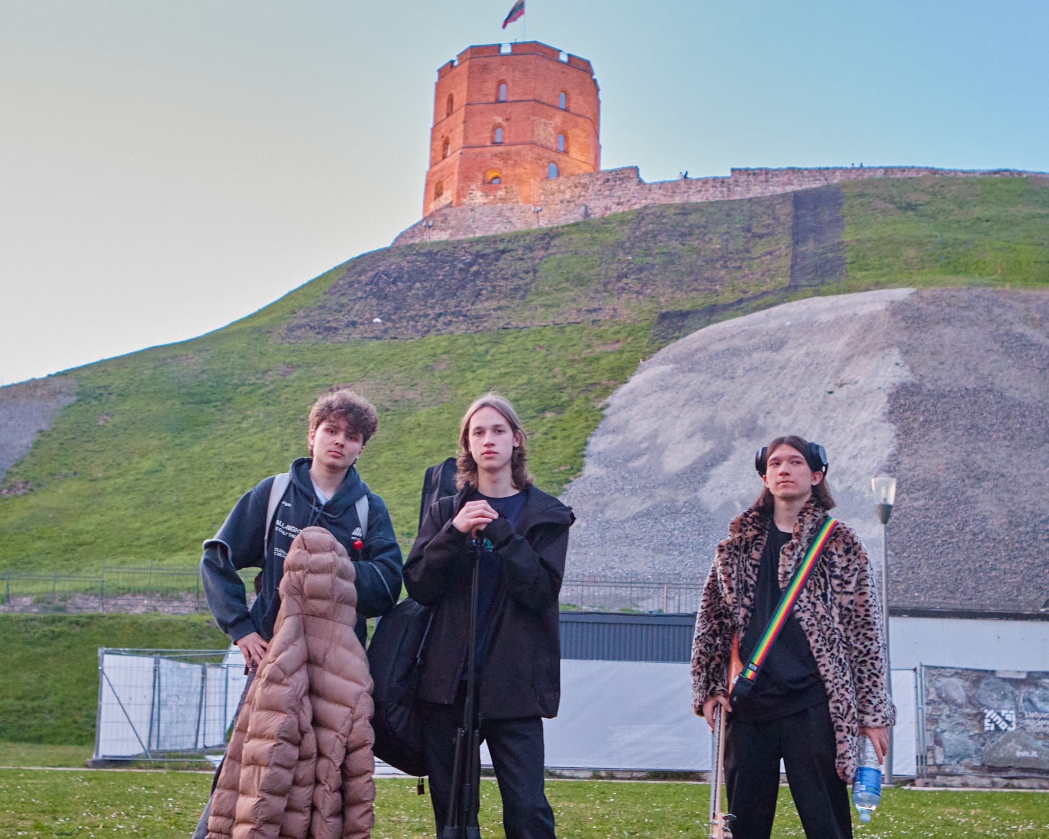 Trys jauni muzikantai pozuoja prie Gedimino pilies kalno