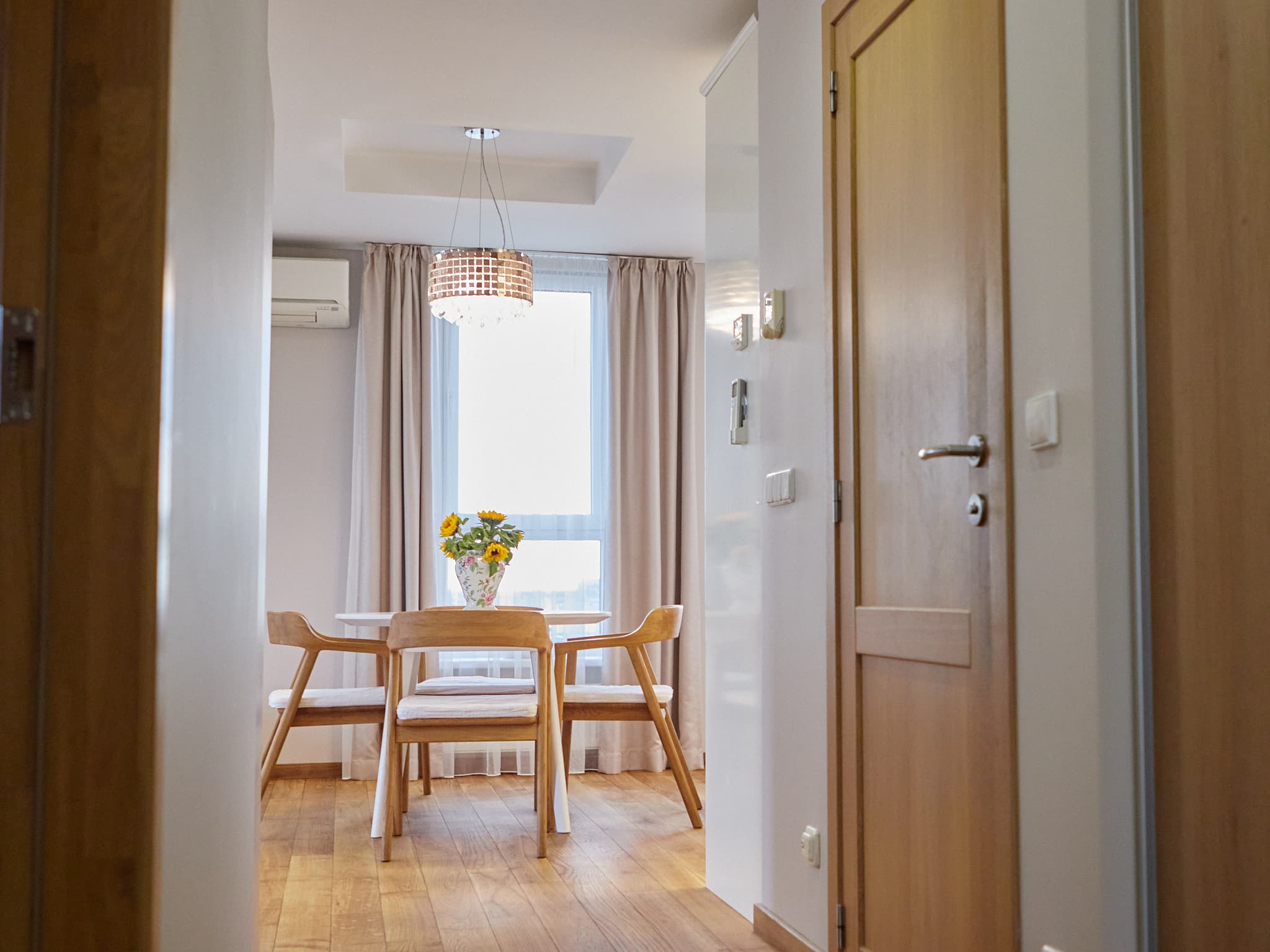 Buto koridoriaus perspektyva į valgomąjį su stalu ir keturiomis kėdėmis