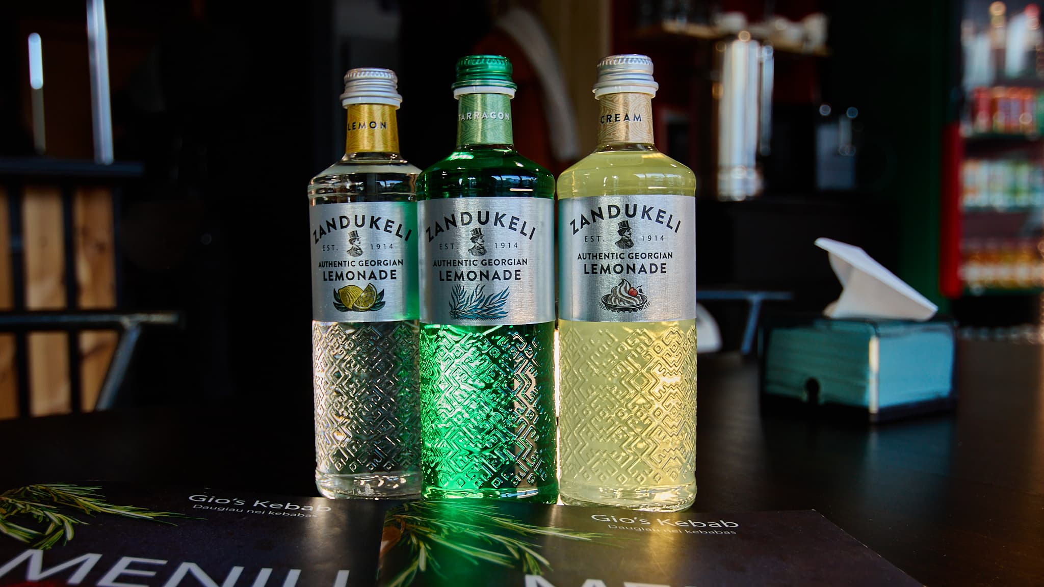 Trys gaiviųjų gėrimų buteliai ant stalo restorano aplinkoje