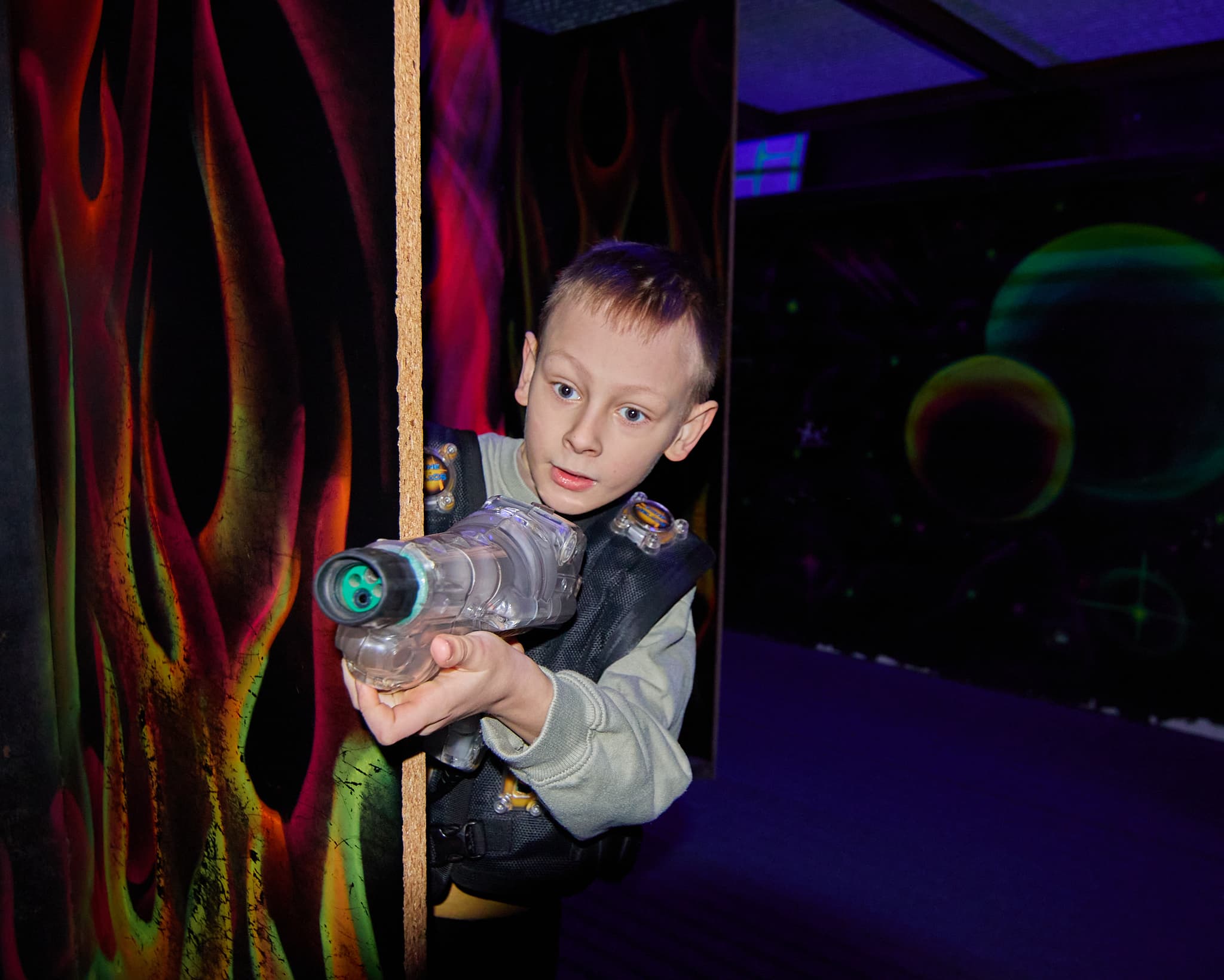 Vaikas su lazerių žaidimo įranga taikosi žaidimų erdvėje