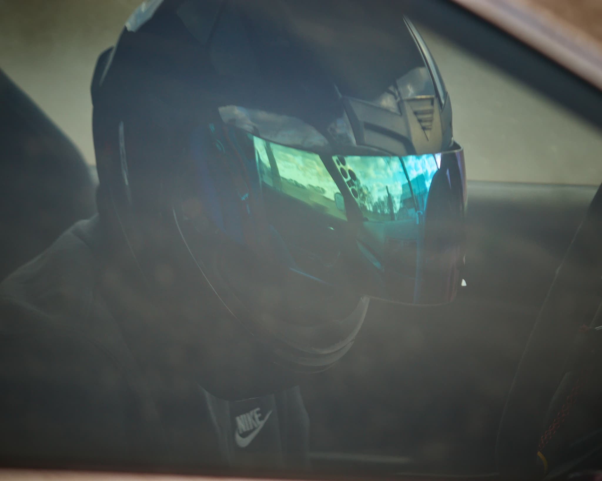 Vairuotojas su šalmu sėdi sportiniame automobilyje