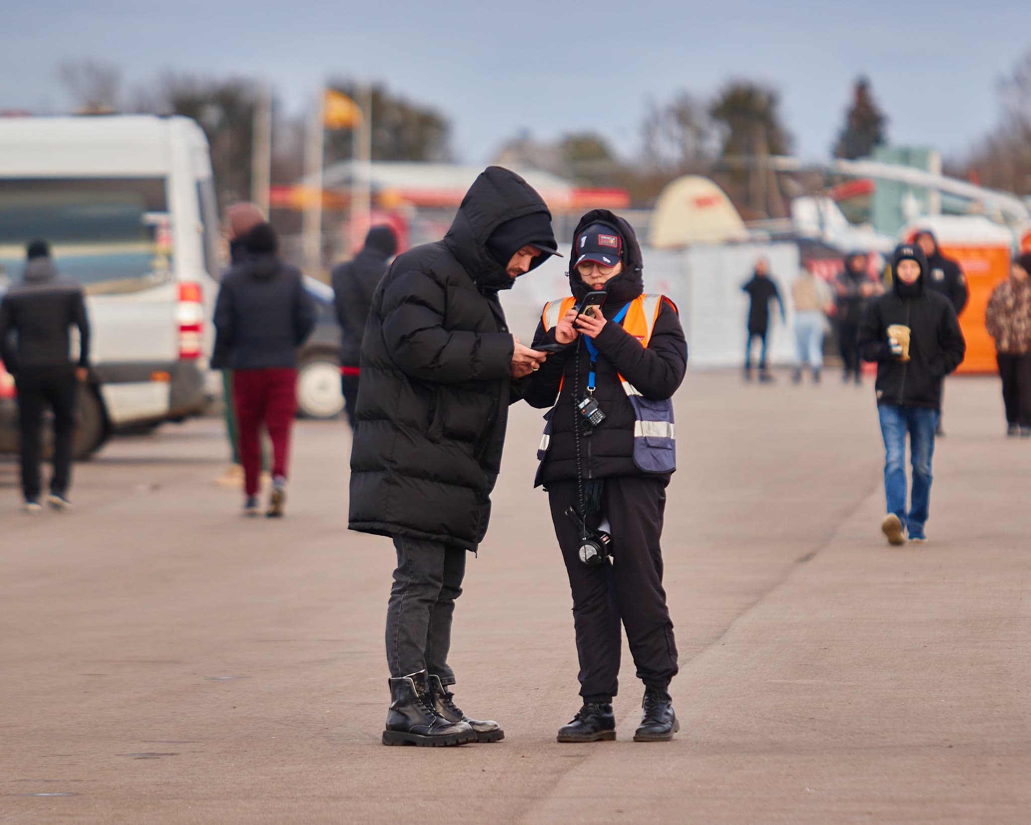 Du renginio komandos nariai aikštelėje tikrina informaciją telefone