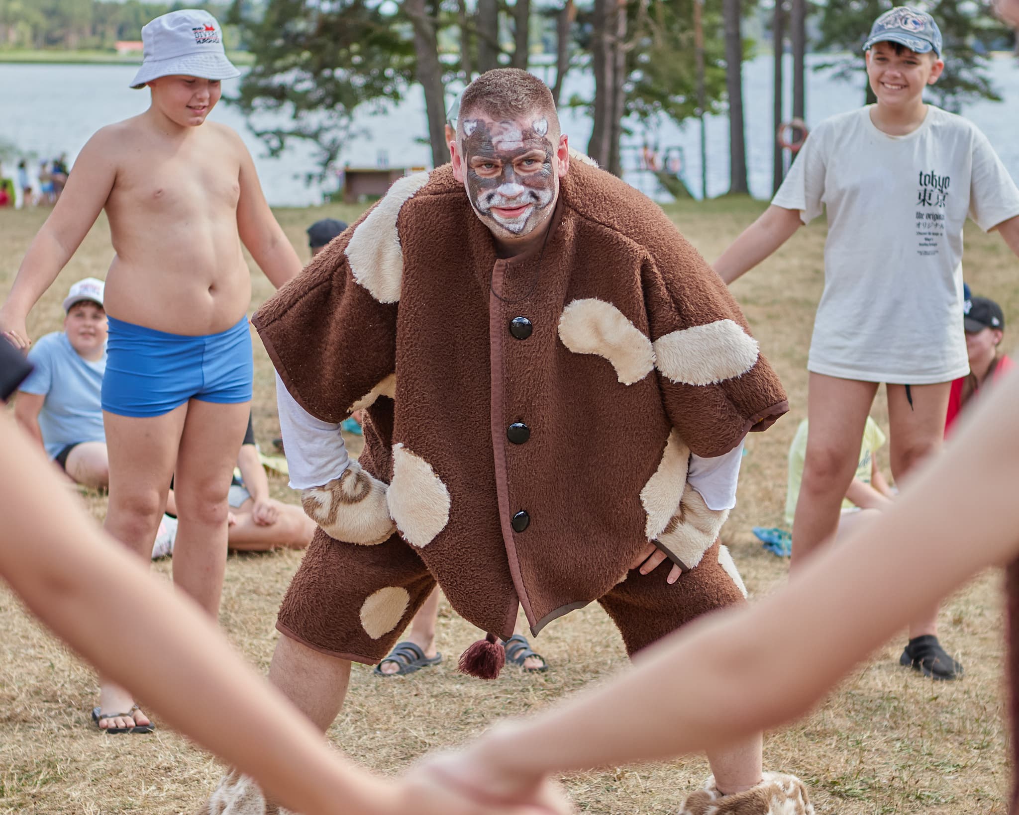 Animatoriaus kostiumu apsirengęs vyras bendrauja su vaikais lauko renginyje