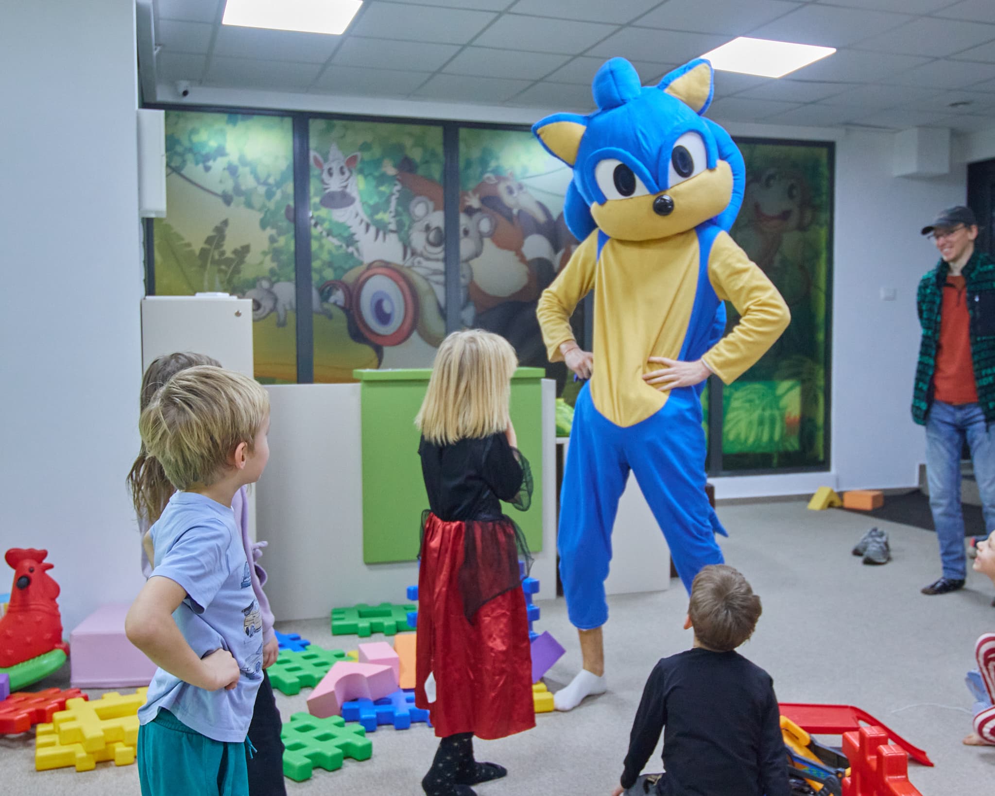 Vaikai žaidimų kambaryje bendrauja su mėlynu personažu