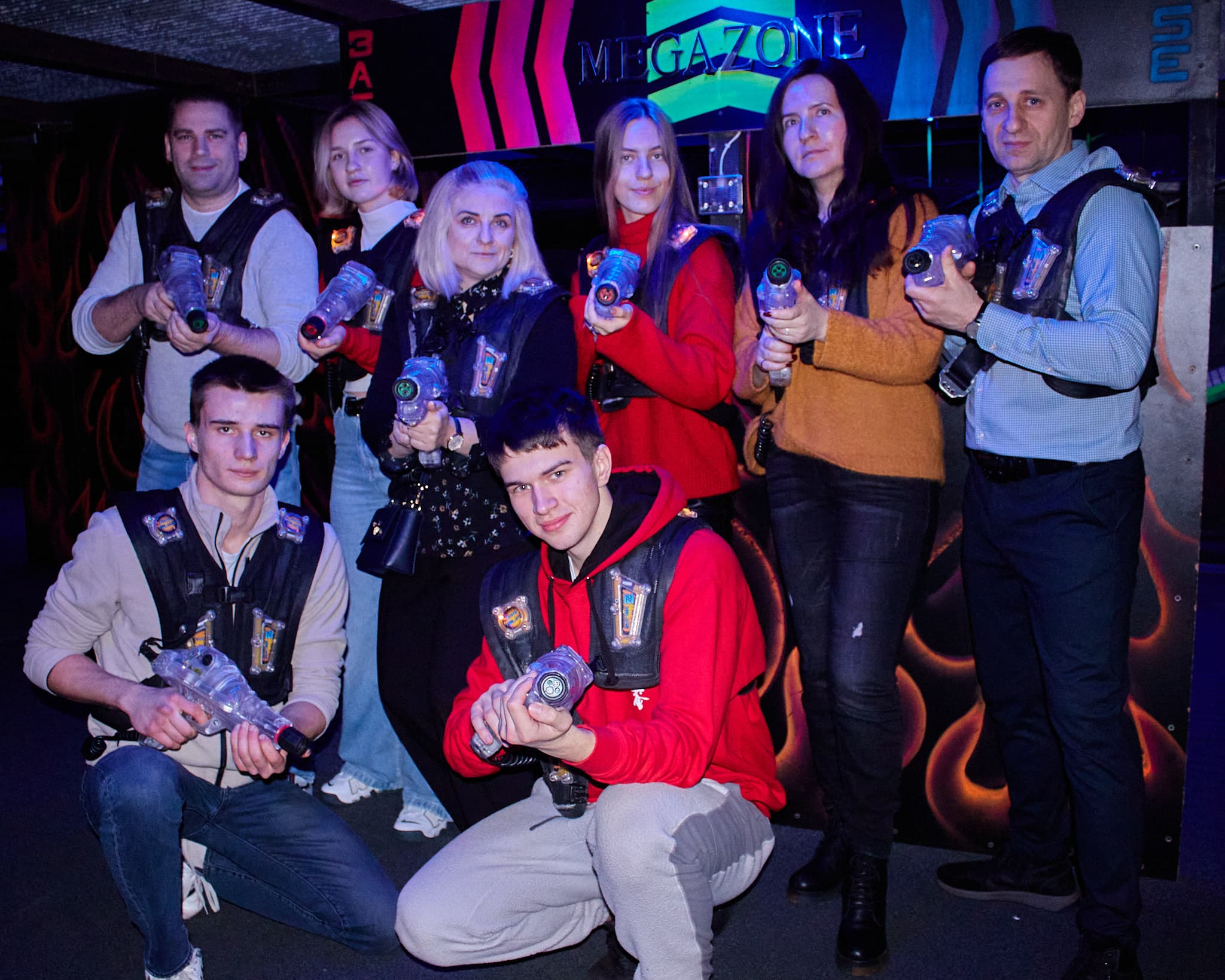 Lazerių arenoje komanda pozuoja su žaidimo įranga