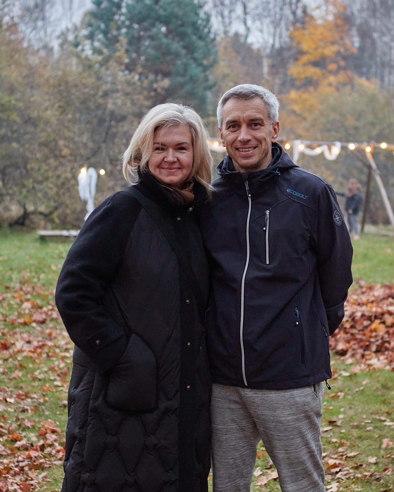 Vyras ir moteris pozuoja rudens parke tarp nukritusių lapų